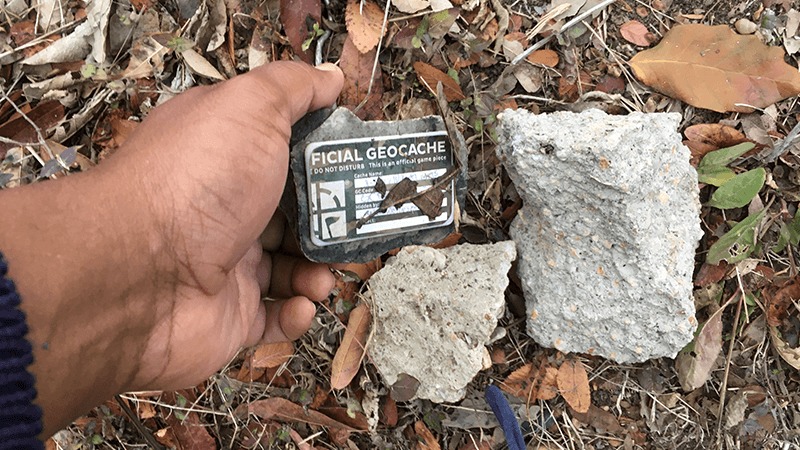 Hand placing a geocache container next to two rocks