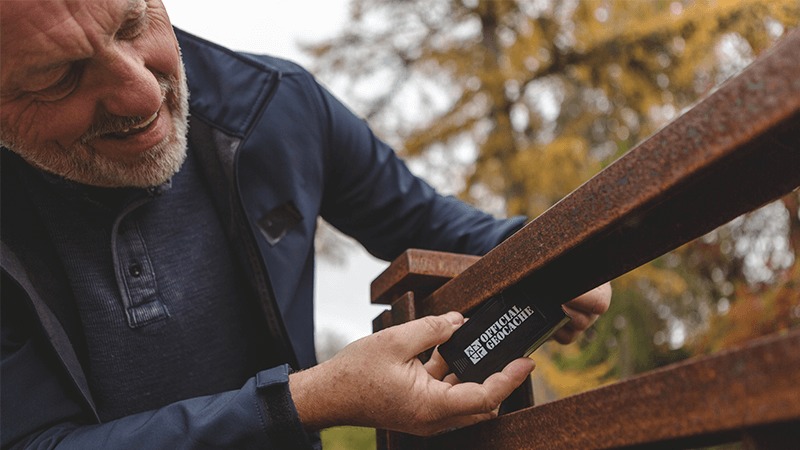 A geocacher finds a micro cache hidden under an outdoor handrailing