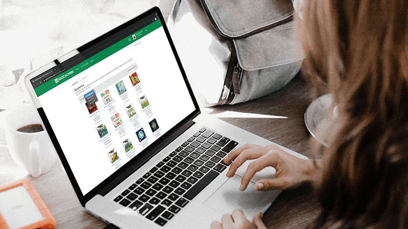 Women at laptop looking at screen of her geocaching souvenirs.